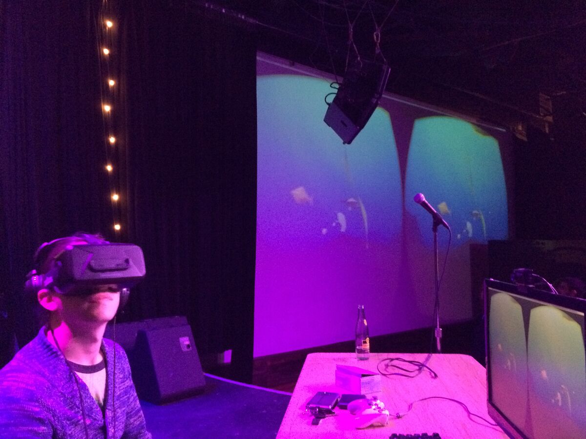 Close-up of an attendee wearing a VR headset experiencing PolyFish, with the underwater scene projected behind them
